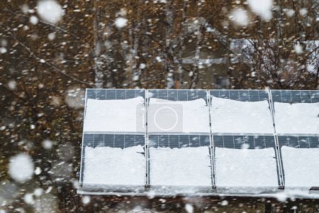 Los paneles solares están cubiertos de nieve en invierno. Instalación de electricidad fotovoltaica durante la temporada de invierno. Producción casera de energía alternativa en clima frío.