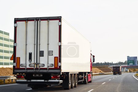 Semitrailer trucks transporting cargo on the highway. The trucks are delivering goods by land from door to door. They are part of a global sustainable logistics industry that supports trade commerce
