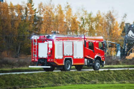 Foto de Un camión de bomberos con una sirena se dirige a un incendio. Lleva bomberos y equipos contra incendios. - Imagen libre de derechos