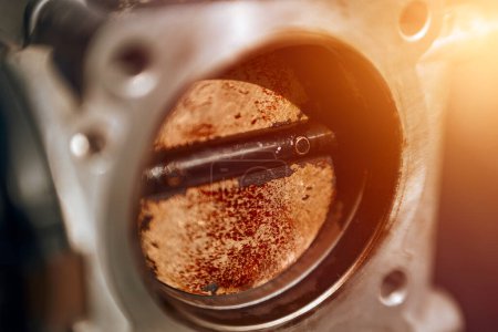 "The effects of carbon on a throttle valve of a car engine". La lame de la vanne est recouverte de saleté et de carbone, ce qui nuit aux performances et à l'efficacité du moteur.