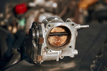 Une soupape d'accélérateur sale dans un moteur de voiture qui doit être nettoyé et calibré pour une meilleure performance et efficacité.
