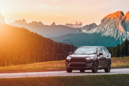 Familia SUV coche en la carretera escénica con el fondo de la puesta del sol