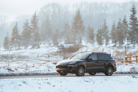 El rendimiento de lujo cumple con el terreno de invierno. SUV alemán negro abraza el camino nevado.