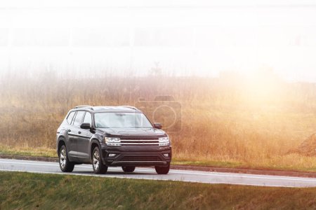 familia moderna SUV viajes en coche a lo largo de una carretera pintoresca con la naturaleza majestuosa y una puesta de sol de oro en el fondo. Camión subcompacto con más capacidades offroad y 4WD