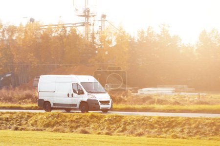 delivery van carries parcels along a sunlit road, ensuring timely service and customer satisfaction.
