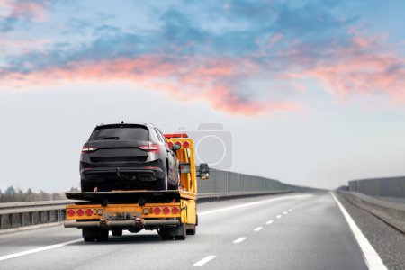Car breakdown and towing. A tow truck with a broken car on a speedway road. Towtruck transporting a car on the highway. Car service transportation concept