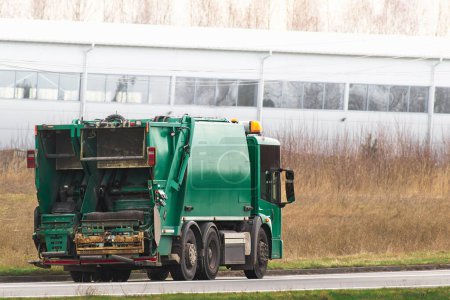Isolated modern waste truck on the road. Sanitation industry. Municipal waste management