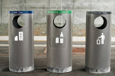 Drei beschriftete Recyclingbehälter für Papier, Flaschen und Abfälle, die zu ökologischer Verantwortung ermutigen. Moderne Wertstofftonnen zur Mülltrennung