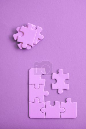 Photo for Purple jigsaw puzzle pieces on purple background with pieces piled and ready to be fit. - Royalty Free Image