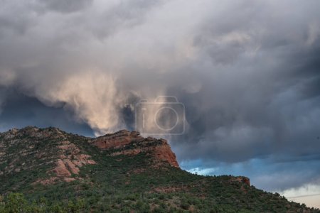 Storm clouds reflect sunlight over red rocks formation near Sedona, Arizona
