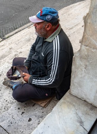 Photo for Rome, Italy - October 22, 2022: A homeless man sits at the entrance to the Basilicas of Santa Maria del Popolo. He asks for mercy. - Royalty Free Image