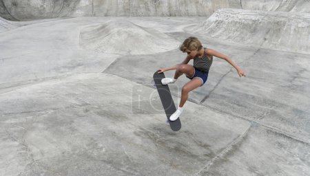 Téléchargez les photos : Une fille monte et fait des tours sur une planche à roulettes sur la rampe d'un skate park. rendu 3D - en image libre de droit