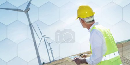 Electrical engineer using digital tablet for wind turbine inspection, geometric pattern