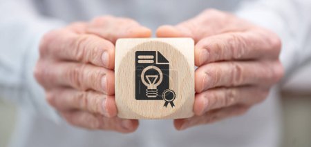 Foto de Mano sosteniendo un cubo de madera con símbolo del concepto de patente - Imagen libre de derechos