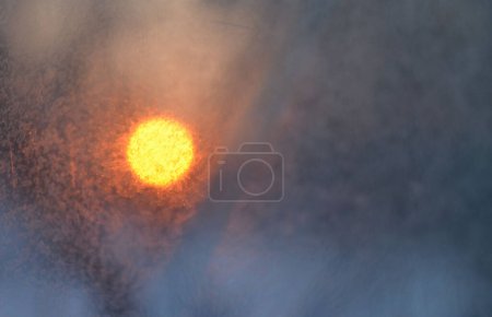 Photo for Photograph of the sun at sunset through the ice on the glass. - Royalty Free Image