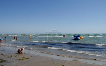 Photo for Sea, blue sky and vacationing adults and children, sand. - Royalty Free Image