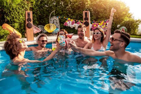Foto de Grupo de amigos dando una fiesta en la piscina, bebiendo cócteles y disfrutando juntos. - Imagen libre de derechos