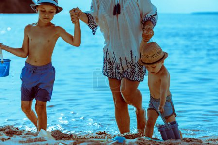 Photo for Mother with two kids playing on the beach, enjoying on summer vacation. - Royalty Free Image