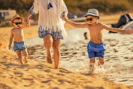 Photo for Mother with two kids playing on the beach, enjoying on summer vacation. - Royalty Free Image