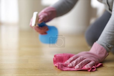 Téléchargez les photos : Gros plan de la femme en gants roses nettoyage du sol avec des détergents à la maison. - en image libre de droit