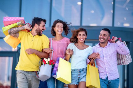 Photo for Group of  friends after shopping walking through city with shopping bags. People,shopping, happiness and lifestyle concept. - Royalty Free Image