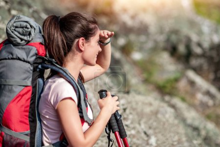 Téléchargez les photos : Jeune femme randonnée à travers la montagne avec des bâtons de randonnée. - en image libre de droit