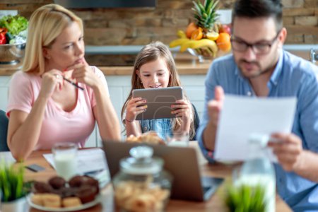 Téléchargez les photos : Portrait de jeune famille calculant ses factures avec sa fille à la maison. - en image libre de droit