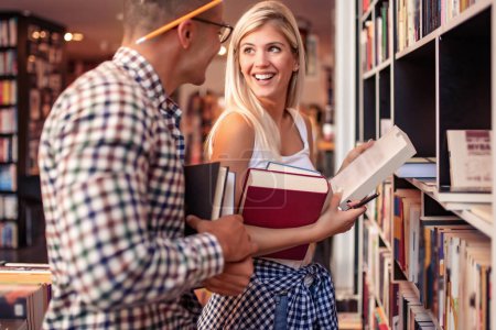 Téléchargez les photos : Jeune couple à la recherche de livres dans la bibliothèque.Concept d'éducation, d'apprentissage et de style de vie. - en image libre de droit