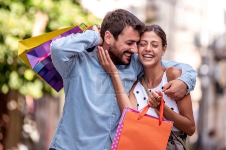 Téléchargez les photos : Portrait de couple heureux avec des sacs à provisions après avoir fait du shopping en ville. - en image libre de droit