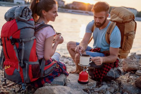 Foto de Montañeros con bolsas, hacen té juntos en su camping. - Imagen libre de derechos