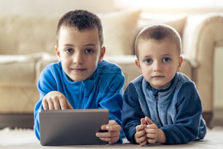 Téléchargez les photos : Garçons jouant à des jeux vidéo sur la tablette à la maison. - en image libre de droit