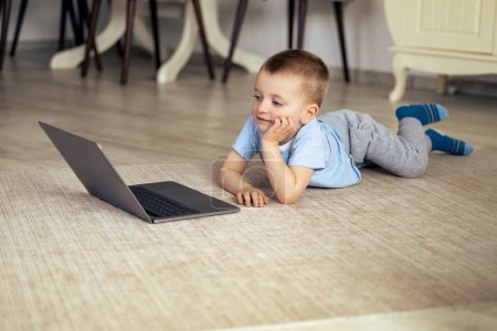 Foto de Niño pequeño con portátil viendo dibujos animados en casa. - Imagen libre de derechos