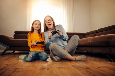 Photo for Weekend at home. Cute little girl with her mom playing video games at home. - Royalty Free Image