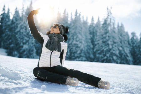 Téléchargez les photos : Femme assise sur la neige dans le parc d'hiver. Concept vacances d'hiver. - en image libre de droit
