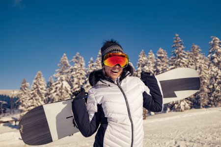 Foto de Felicidad, vacaciones de invierno, turismo, viajes y concepto de personas. Mujer snowboarder de pie con snowboard. - Imagen libre de derechos