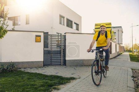 Photo for Happy smiling delivery man with thermal backpack on city street,he is ridind a bicycle. - Royalty Free Image