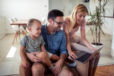 Téléchargez les photos : Jeune famille caucasienne regardant l'ordinateur portable ensemble à la maison. - en image libre de droit