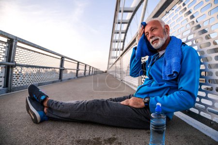Foto de Hombre mayor descansando después de hacer ejercicio en la mañana al aire libre. Fitness, deporte y estilo de vida saludable. - Imagen libre de derechos