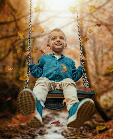 Téléchargez les photos : Petit garçon jouer dans le parc d'automne.Amusement en plein air en famille en automne. Tout-petit à l'automne.Petit garçon balançant. - en image libre de droit