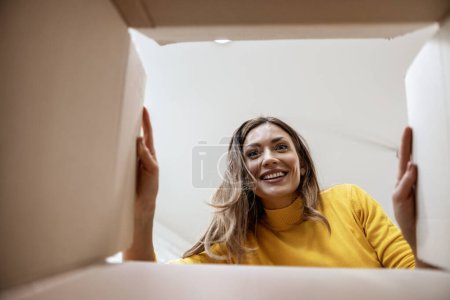 Téléchargez les photos : Femme avec boîte ouverte, vue de l'intérieur.Paquet excité de livraison de carton de déballage.Surprise. - en image libre de droit
