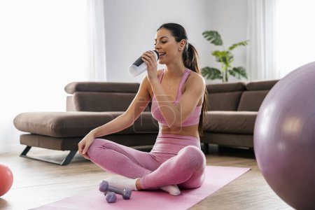 Téléchargez les photos : Femme de fitness faisant de l'exercice dans le salon. Fille attrayante exerçant à la maison.Formation en ligne. - en image libre de droit