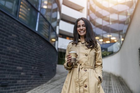 Photo for Portrait of successful businesswoman holding coffee on her way to work on city street. - Royalty Free Image