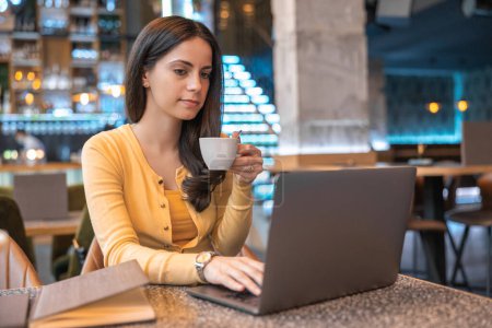 Photo for Portrait of an attractive young woman using laptop at a cafe. Woman working on laptop computer at a coffee shop. - Royalty Free Image