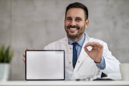 Téléchargez les photos : Portrait du médecin masculin tenant une tablette numérique et montrant l'espace libre.. - en image libre de droit