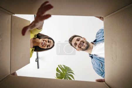 Téléchargez les photos : Heureux jeune couple marié déménage dans un nouvel appartement et boîtes débordantes.Couple souriant boîtes débordantes dans une nouvelle maison. - en image libre de droit