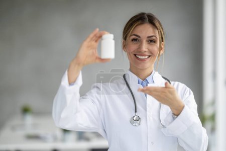 Téléchargez les photos : Portrait d'une femme médecin tenant une bouteille de médicaments et montrant l'espace libre.. - en image libre de droit