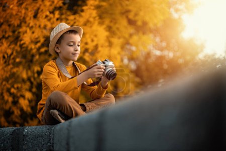 Téléchargez les photos : Portrait d'automne de mignon petit garçon caucasien à l'extérieur.Petit garçon prenant des photos, à l'aide d'une caméra de film vintage. - en image libre de droit