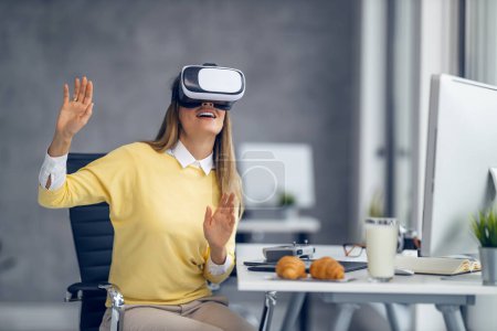 Téléchargez les photos : Jeune femme d'affaires utilisant son appareil VR au bureau.Elle s'amuse et s'amuse au bureau. - en image libre de droit