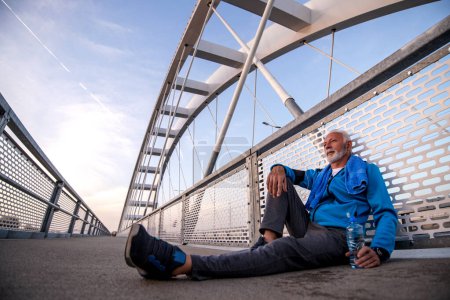 Téléchargez les photos : Homme âgé se reposant après l'entraînement à l'extérieur et boire de l'eau. Fitness, sport et mode de vie sain. - en image libre de droit