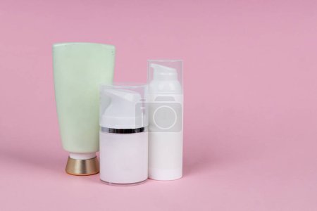 Téléchargez les photos : White containers of cosmetics on pink background. Skincare product set. Face and body care concept. - en image libre de droit